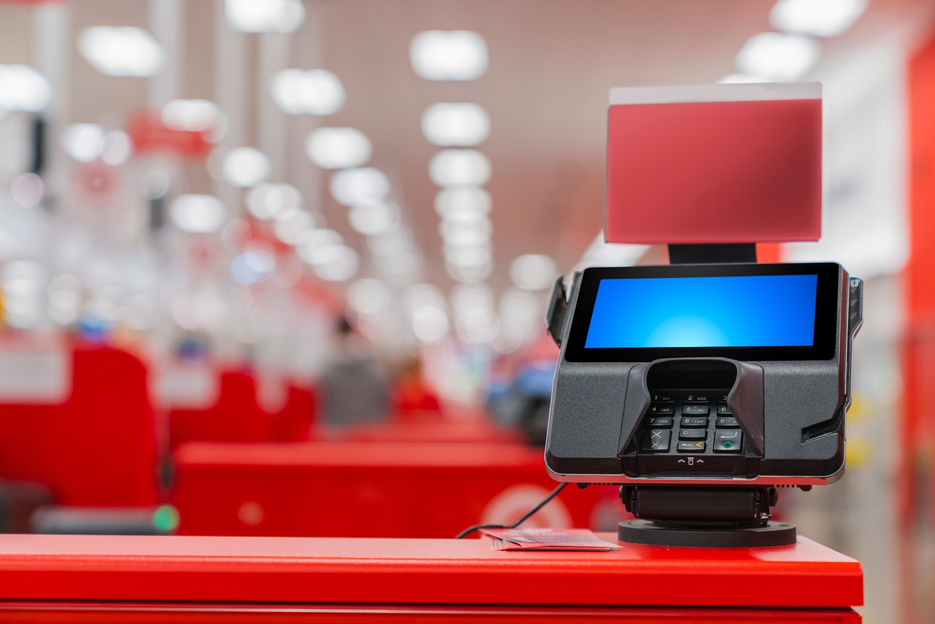 A POS machine at Woolworths Supermarket's self-serve checkout area with blur bokeh background